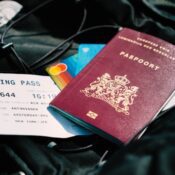 A close-up of hands holding a passport and a visa application form, with a magnifying glass over the form.