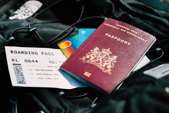 A close-up of hands holding a passport and a visa application form, with a magnifying glass over the form.